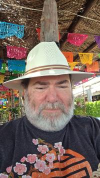 An older gentleman wearing a Panama hat with grey beard and mustache